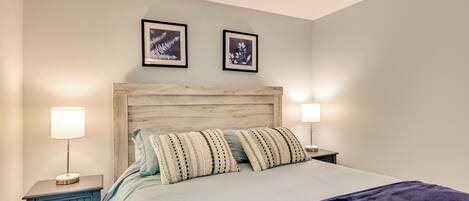 A neatly made bed with striped pillows, a wooden headboard, and two bedside lamps.