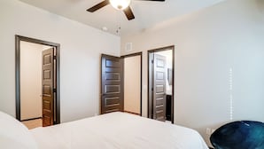 Ein Schlafzimmer mit einem Bett, einem Deckenventilator und drei Türen.