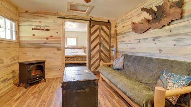 L’intérieur chaleureux d’un chalet avec des murs en bois, un canapé, une commode et une cheminée.