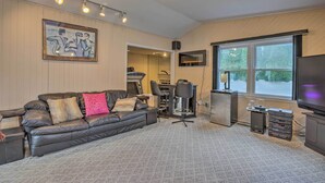 Un salon moderne avec un canapé en cuir, une table basse, un téléviseur et un coin bar équipé d’un réfrigérateur et d’un four à micro-ondes.