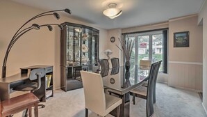 Un espace de salle à manger moderne avec une table à plateau en verre, des chaises noires et un luminaire au plafond au design incurvé et original.