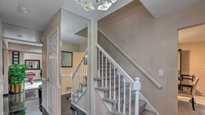 Un intérieur moderne avec un escalier, une plante en pot et une porte vitrée donnant sur une autre pièce.