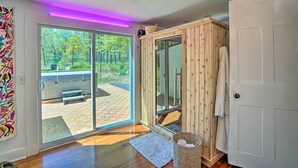 A room with a sliding glass door to a patio, a wooden cabinet, and a white door. - Eclectic Troy Home w/ Hot Tub - Pet Friendly! (Troy)