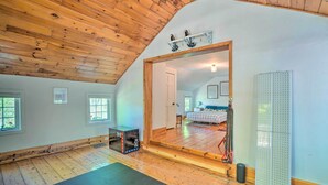 A spacious room with wooden flooring, a large mirror, and a yoga mat. - Eclectic Troy Home w/ Hot Tub - Pet Friendly! (Troy)