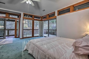 A bedroom with a large bed, multiple windows, and a ceiling fan. - Home With Wraparound Deck + Blue Ridge Mtn Views! (Radford)