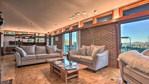 A spacious living room with two sofas, a coffee table, and a large window with a view of the outdoors. - Home With Wraparound Deck + Blue Ridge Mtn Views! (Radford)
