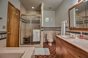 A bathroom with a bathtub, a sink, a toilet, a glass-enclosed shower, and a wooden door. - Home With Wraparound Deck + Blue Ridge Mtn Views! (Radford)
