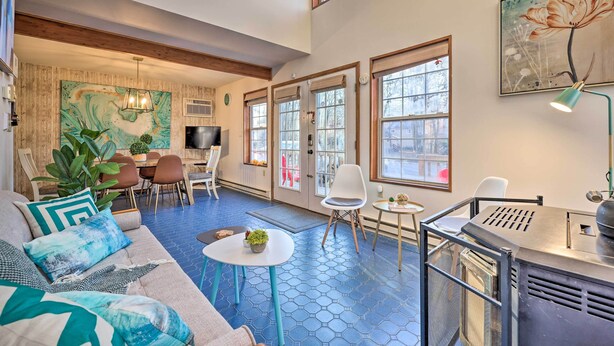 A spacious living area with a blue hexagonal floor, a sofa with teal cushions, a dining table, and a grill station. - Modern Poconos Gem w/ Fire Pit, Deck & Pool Access (Tobyhanna)