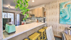 A kitchen with wooden cabinets, a marble countertop, and a bar stool area. - Modern Poconos Gem w/ Fire Pit, Deck & Pool Access (Tobyhanna)