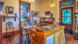 Una cocina con armarios de madera, una isla central con un lavamanos y una zona de comedor con sillas y una mesa.