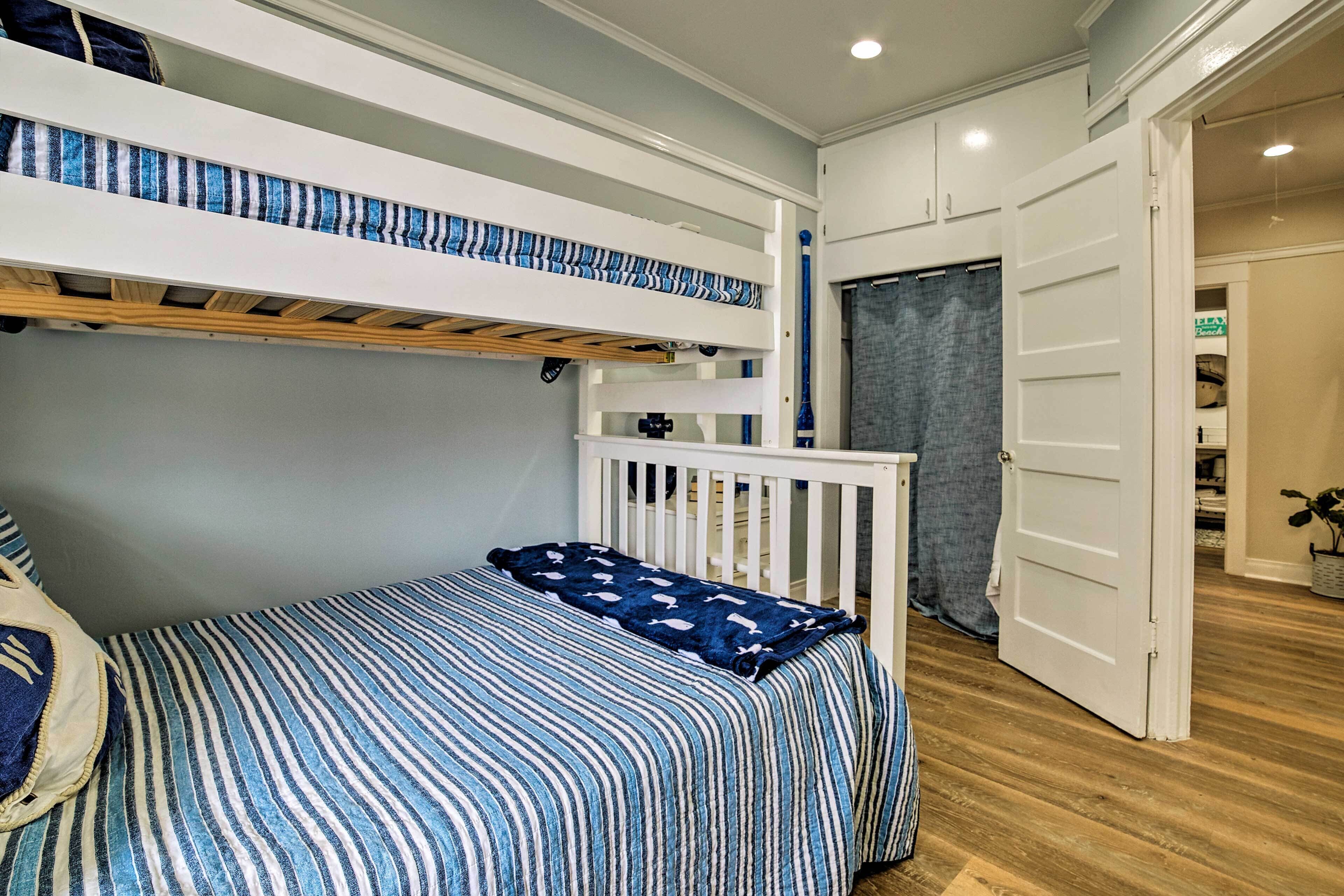 Une chambre avec un lit superposé, un lit simple et une porte donnant sur une autre pièce.
