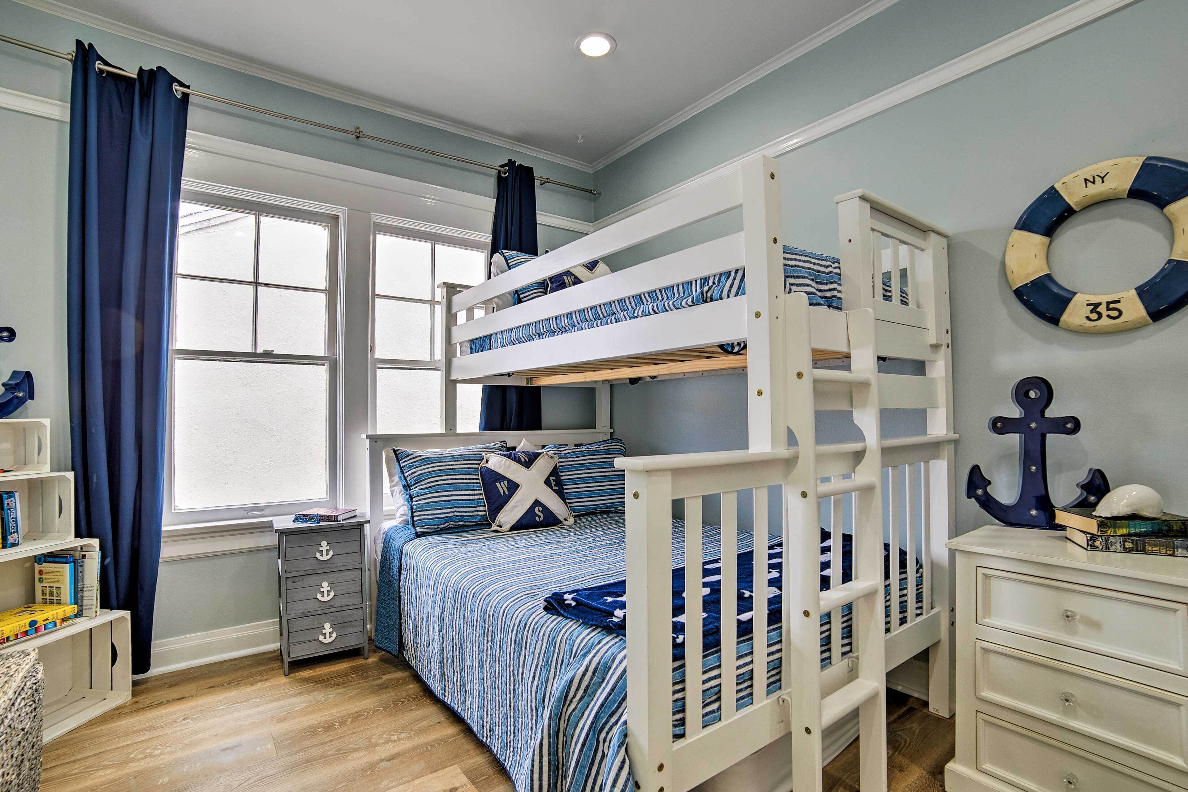 Une chambre à coucher décorée sur le thème de la marine, avec des lits superposés, une commode et une fenêtre avec des rideaux.