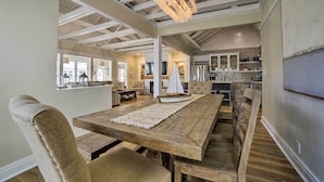 Un'ampia sala da pranzo con un tavolo e sedie in legno, un centrotavola a forma di barca a vela decorativa e una cucina moderna sullo sfondo.