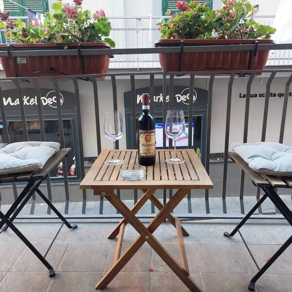 An outdoor seating area with a table, two chairs, a bottle of wine, and two glasses.