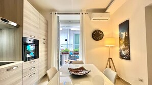 A modern kitchen with a built-in oven and a dining area with a glass table and white chairs.