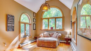 Une pièce chaleureuse avec une grande fenêtre, un canapé confortable et un plancher en bois.