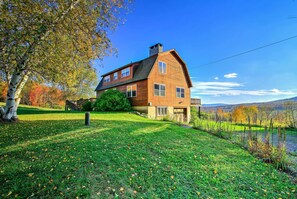 A large, two-story wooden house with a prominent chimney, surrounded by a well-maintained lawn and a small pond. - 'bearpen Lodge' on 125 Acres - Near Belleayre Mtn! (Fleischmanns)