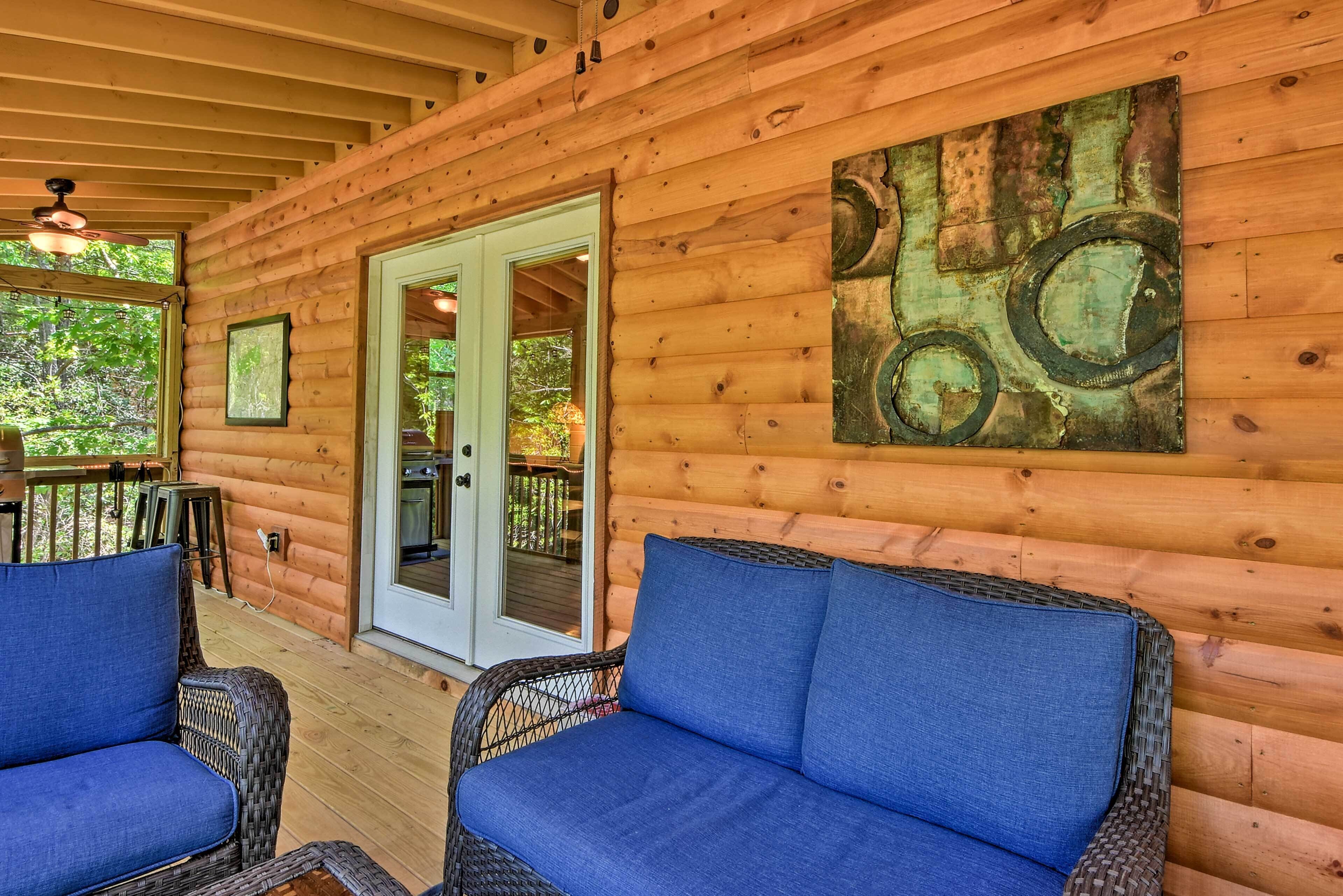 A log cabin with a porch, wicker furniture, and a door leading to an outdoor area.