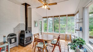 A room with a wooden table and chairs, a ceiling fan, a fireplace, and large windows offering a view of greenery. - Breweries, Hiking Trails & Museums: Monument House (Monument)