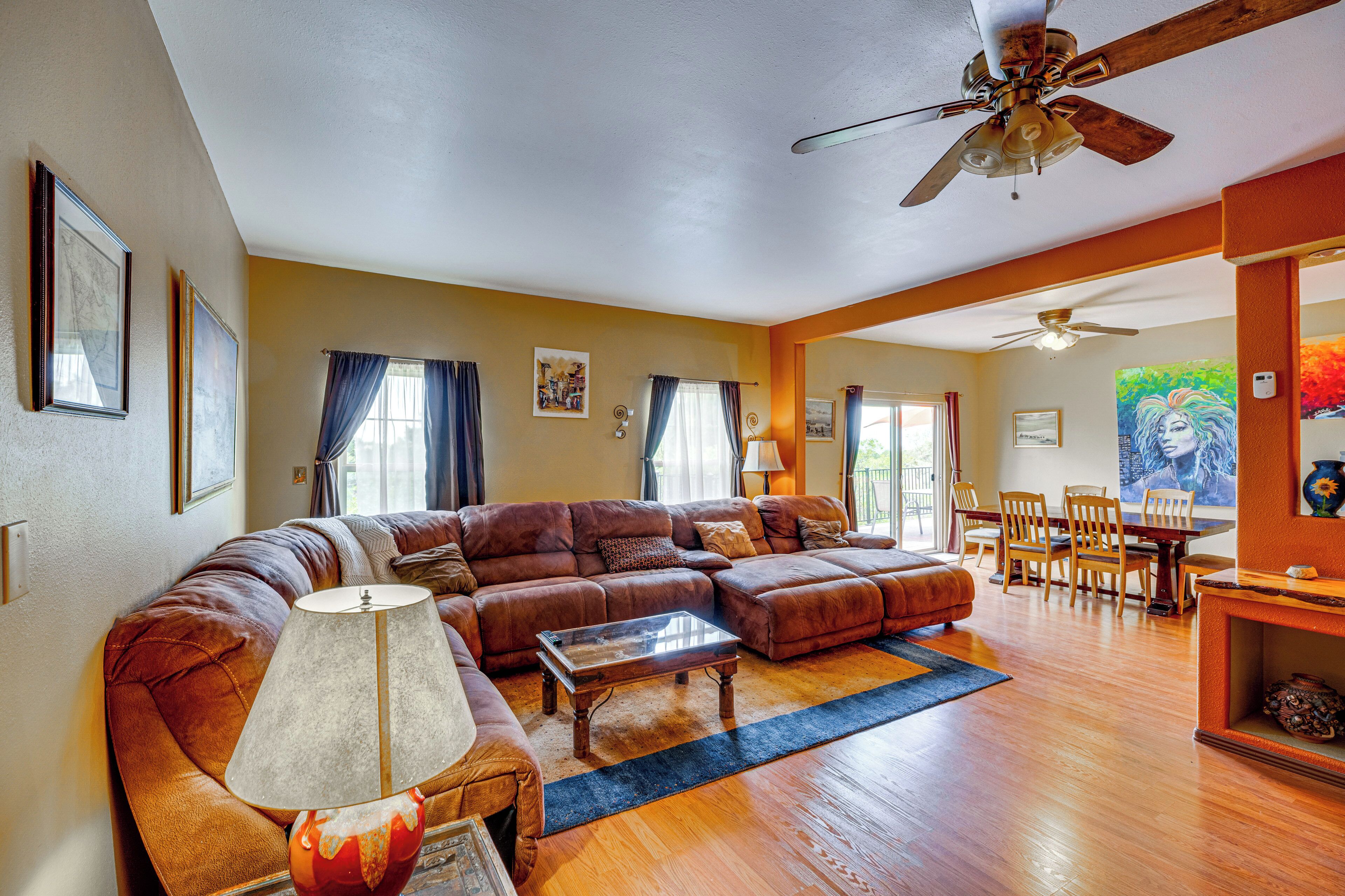 A spacious living room with a large sectional sofa, a coffee table, and a dining area with chairs and a table.