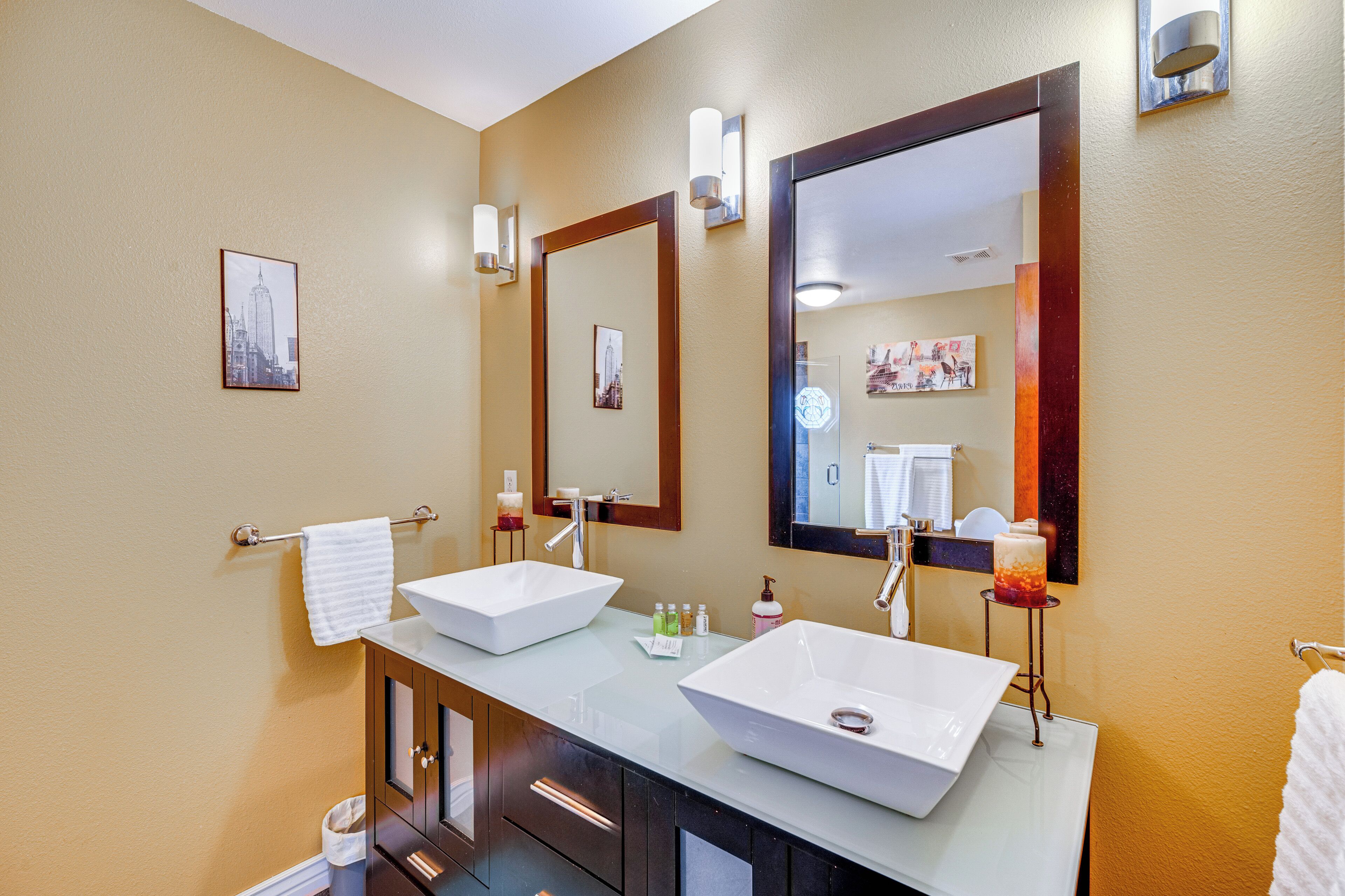 A modern bathroom with two large vessel sinks, a mirror, and a towel rack.