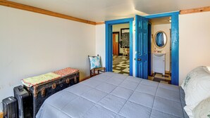 A bedroom with a bed, a suitcase, a chair, and a bathroom visible through an open door. - Family ATV Adventure Hub! Renovated Rental in Gary (Gary)