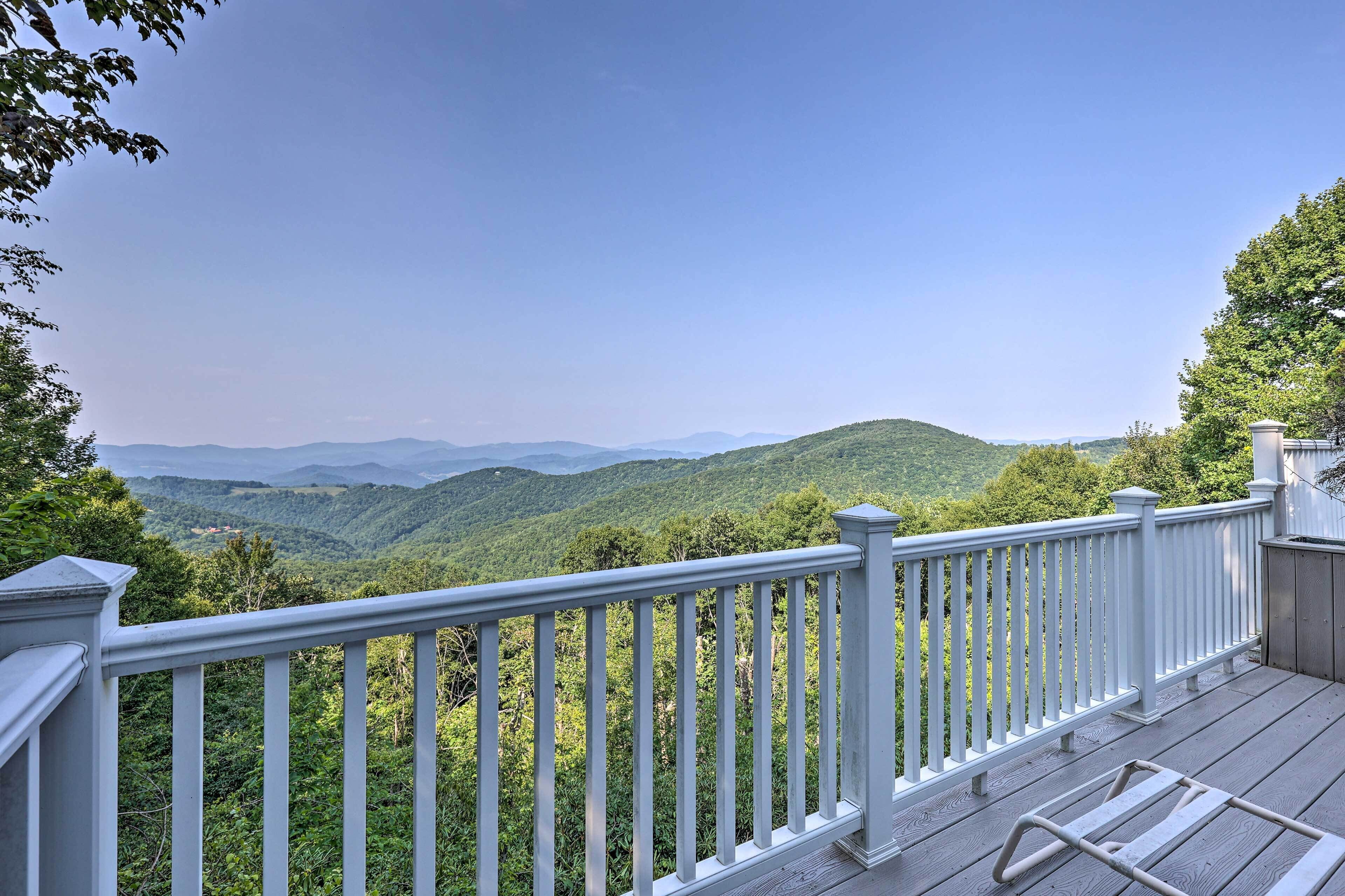 A deck with a white railing overlooking a mountainous landscape.