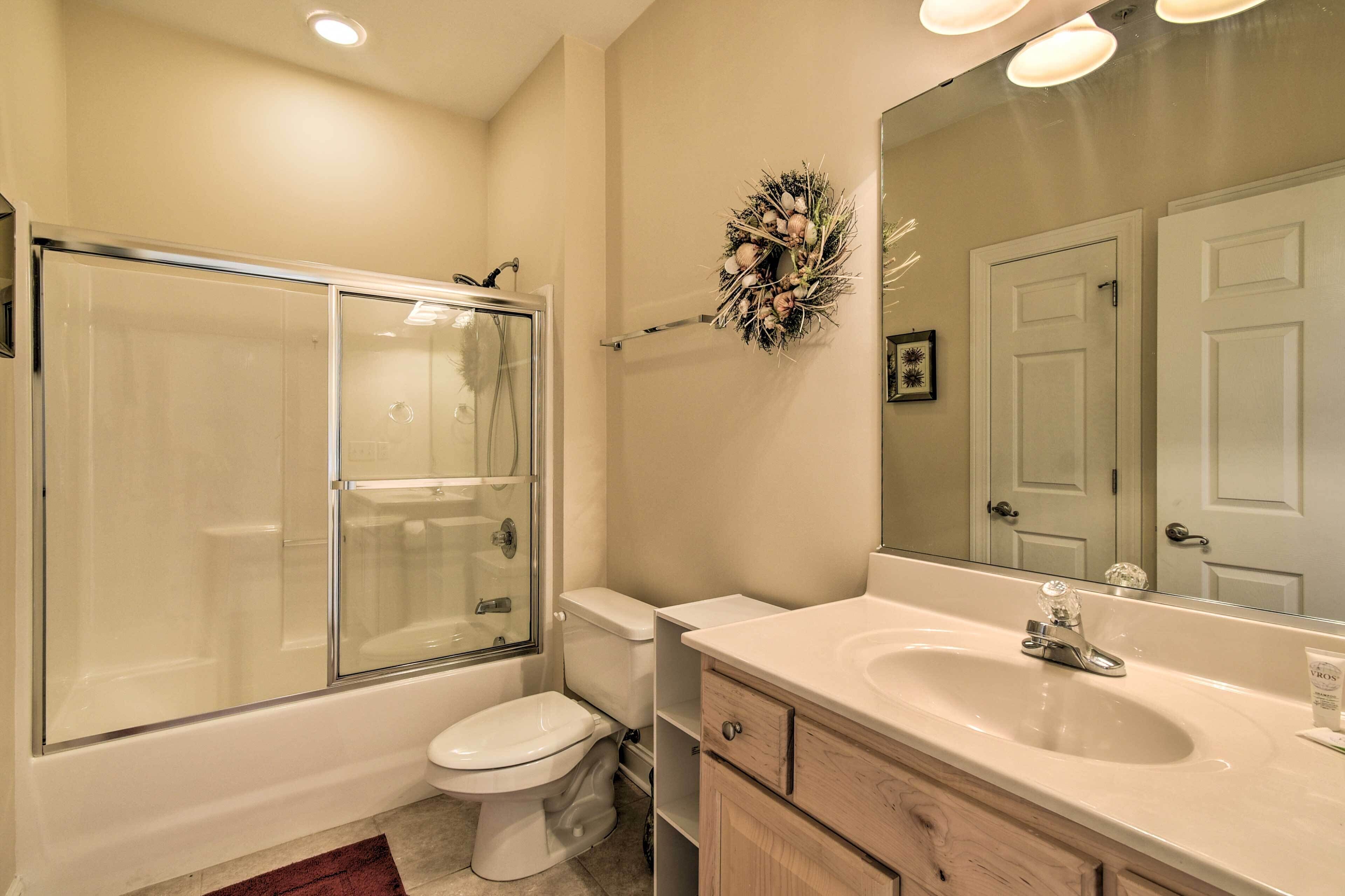 A bathroom with a glass-enclosed shower, a toilet, a sink, and a mirror.