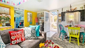 A brightly colored living room with a sofa, a dining table, and a chandelier. - Oceanfront White Stone Cottage w/ Private Beach! (White Stone)