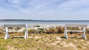 Two white benches facing a beach with a clear sky. - Oceanfront White Stone Cottage w/ Private Beach! (White Stone)