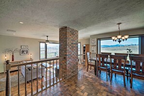 A spacious living area with a brick fireplace, wooden dining table, and chairs.