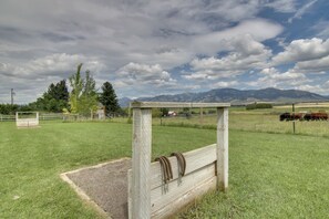 A rural landscape with a wooden fence, a metal gate, and a grassy field.