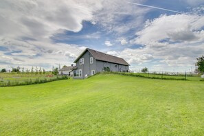A large, single-story house with a sloped roof, surrounded by a well-maintained lawn and a wooden fence. - Bozeman Home on 11 Acres w/ Mountain Views! (Bozeman)