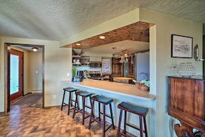 A kitchen with a bar area, wooden stools, and a herringbone floor pattern. - Bozeman Home on 11 Acres w/ Mountain Views! (Bozeman)