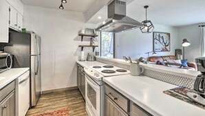 A modern kitchen with stainless steel appliances, a white countertop, and a wooden floor. - Condo w/ Balcony & Views - Steps to Ski Shuttle! (Fraser)