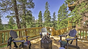 Une terrasse dotée de chaises Adirondack, d’un foyer et d’une rambarde en bois.
