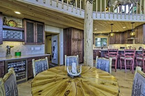 Un intérieur rustique avec une table ronde en bois, des chaises en bois, un coin cuisine avec des placards en bois et un balcon doté de balustrades en bois.