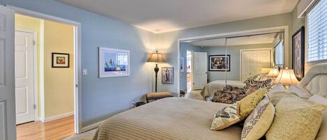 A bedroom with a large bed, a bedside table, a lamp, and a mirror.