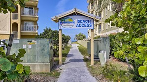 A pathway leading to a building with a sign indicating beach access. - Resort Condo w/ Beach Access in Indian Shores! (Indian Shores)