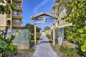 Un sentiero che conduce a un edificio con un'indicazione per l'accesso alla spiaggia.