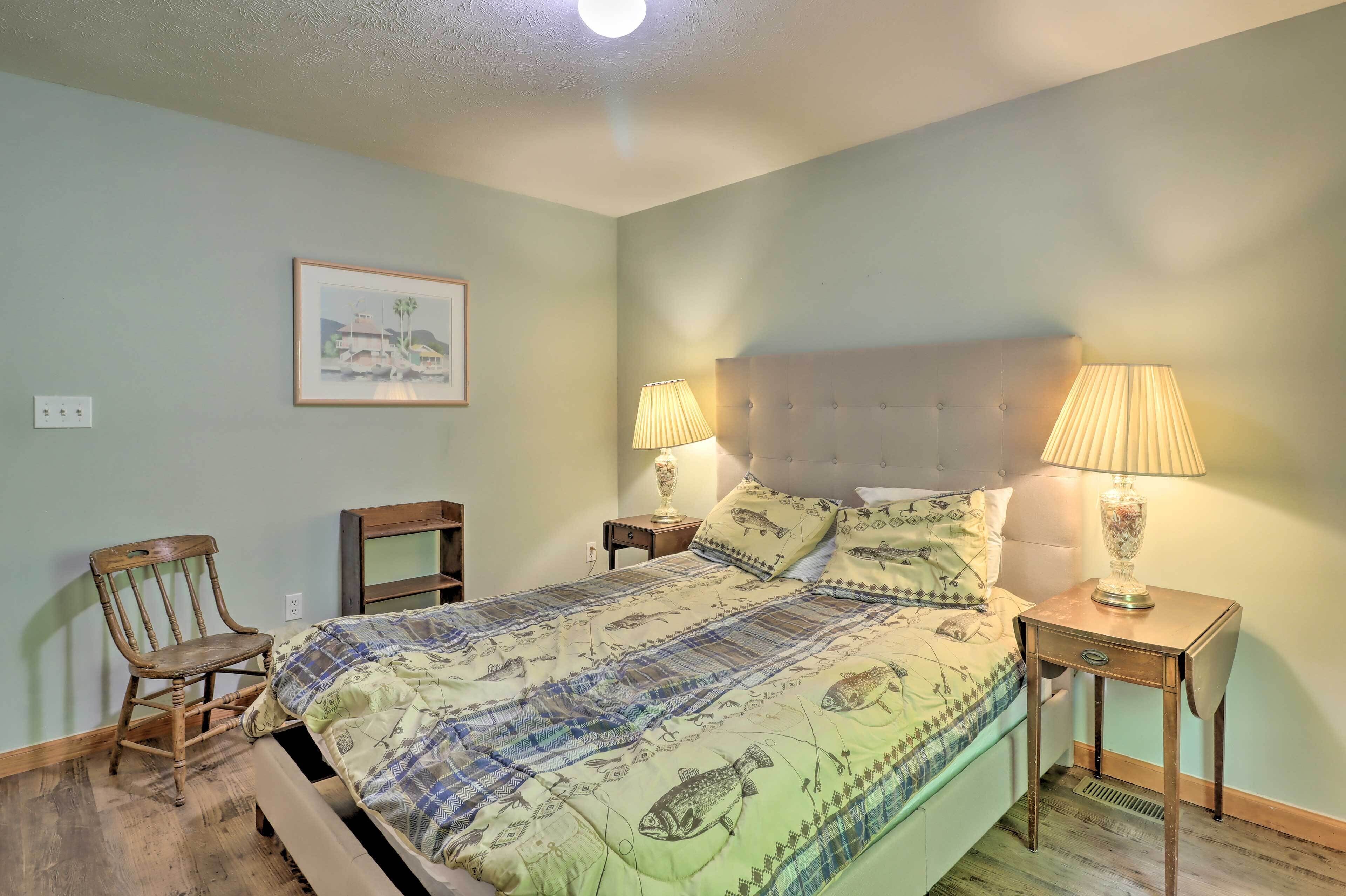 A bedroom with a bed, two nightstands, a chair, a lamp, and a framed picture on the wall.