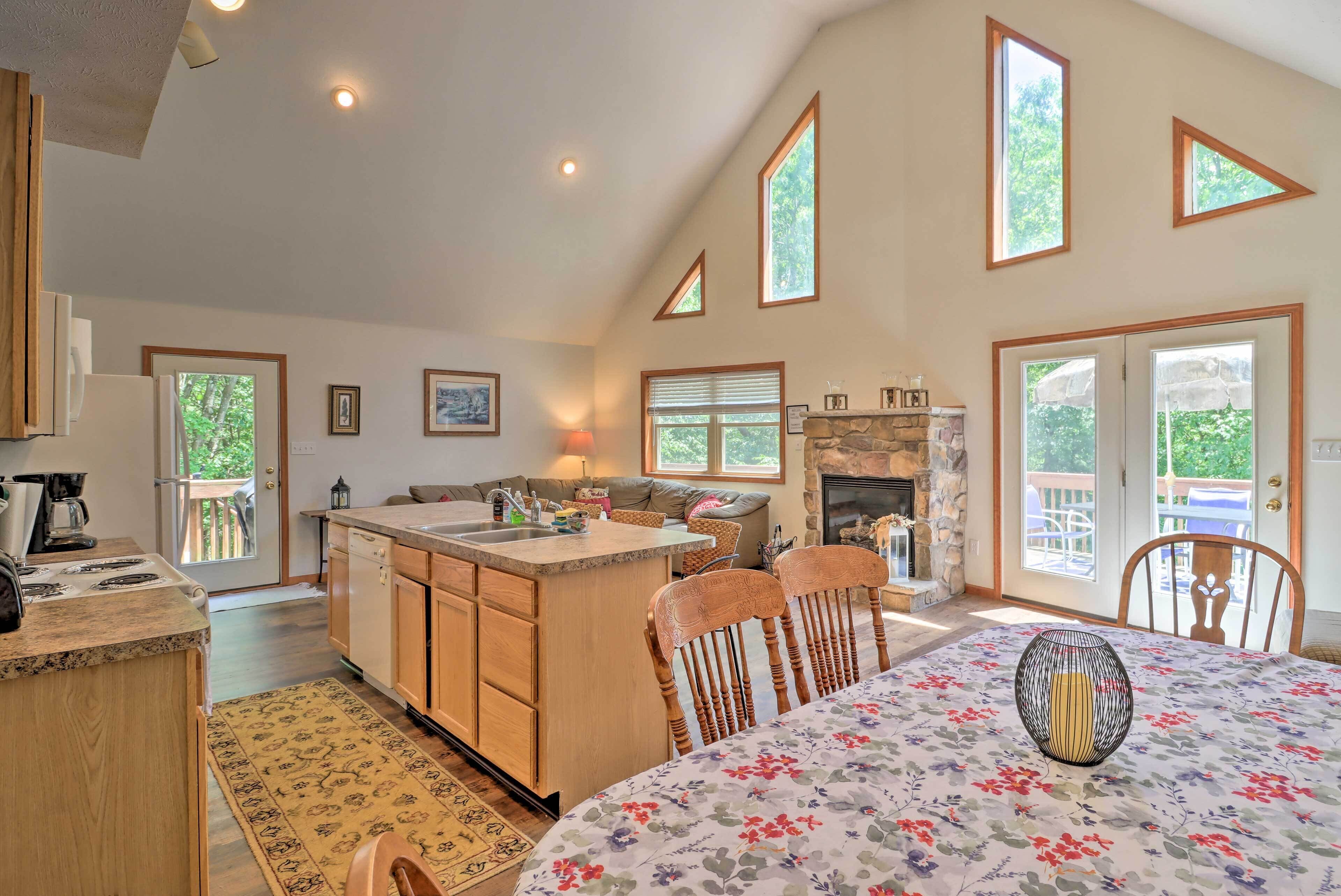 A spacious kitchen with a central island, wooden cabinets, and a dining area with a floral tablecloth.