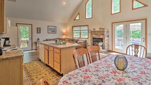 A spacious kitchen with a central island, wooden cabinets, and a dining area with a floral tablecloth. - Deck, Hot Tub & Game Room: Lake Harmony Home (Lake Harmony)