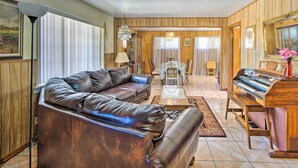 A living room with a brown leather sofa, a wooden piano, and a dining table with chairs. - El Paso Home < 1 Mi to Lone Star Golf Club! (El Paso)