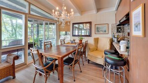 A spacious dining area with a wooden table, wicker chairs, and a yellow armchair. - Waterfront White Lake Vacation Rental! (Kauneonga Lake)