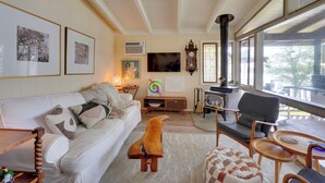 A cozy living room with a white sofa, a wooden coffee table, and a fireplace. - Waterfront White Lake Vacation Rental! (Kauneonga Lake)
