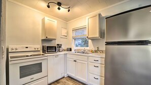 Una cocina con muebles blancos, un refrigerador de acero inoxidable, un microondas y un horno.