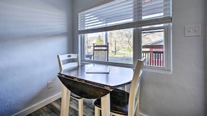 Un comedor con una mesa y sillas, una ventana con persianas y vistas al exterior.