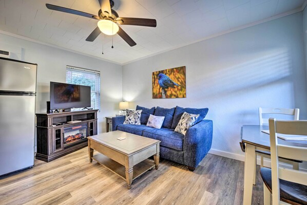 A living room with a blue sofa, wooden coffee table, and a TV on a stand.