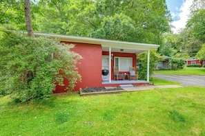 A red single-story house with a covered porch, a barbecue grill, and a small garden area.